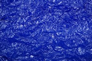 Crumpled cellophane bright blue transparent plastic paper texture abstract background. photo