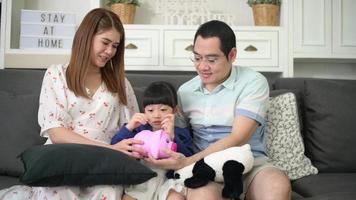 An asian family is teaching daughter on savings money with a piggy bank, financial planning concept video