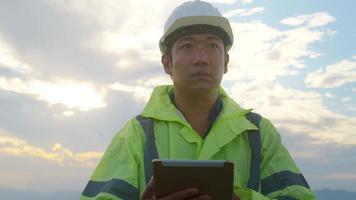 Ein Ingenieur trägt einen Schutzhelm auf dem Kopf und verwendet Tablet-Analyse-Engineering-Daten. video