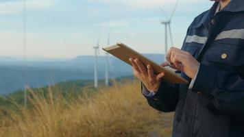 una ingeniera lleva un casco protector en la cabeza y utiliza datos de ingeniería de análisis de tabletas. video