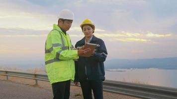 el ingeniero de personas lleva un casco protector en la cabeza, utilizando datos de ingeniería de análisis de tabletas. video