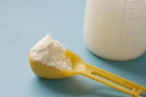 Close up of baby milk powder and spoon on blue background photo