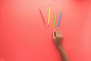 child hand pick color pencils on red background photo