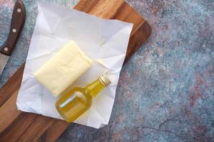 rebanada de mantequilla en un papel y aceite en una tabla de cortar en la mesa foto
