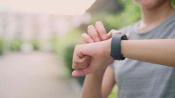 Nahaufnahme der Fitnessfrauenhände berühren ihre Smartwatch, starten Sie die App vor dem Training, das Fitnesstechnologiekonzept