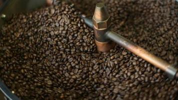 el grano de café se está asando en la máquina tostadora, fumando del café. video