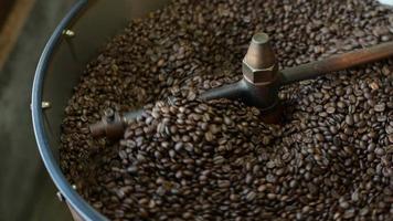 el grano de café se está asando en la máquina tostadora, fumando del café. video