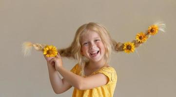 Laughing girl with yellow flowers in braids photo