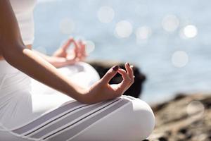 Young woman doing yoga in the beach wearing white clothes photo