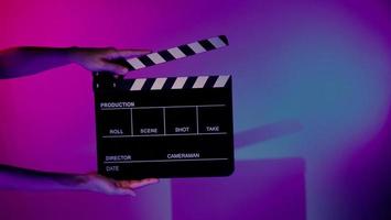 Hand holds empty film making clapperboard on color background in studio photo