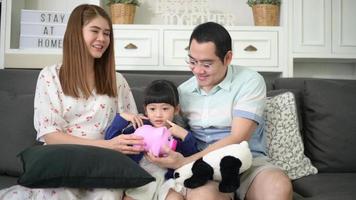 An asian family is teaching daughter on savings money with a piggy bank, financial planning concept video