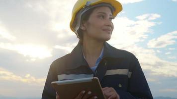 a woman engineer is wearing a protective helmet on her head, using tablet Analytics engineering data. video