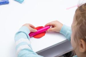 The girl at the table is playing with modeling dough. Childrens games for fine motor skills photo