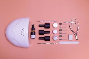 Top view of tools and materials for modern gel manicure and nail extension. Knolling on color background. Flat lay manicure tools photo