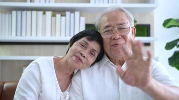 un anciano feliz asiático está haciendo videollamadas, se relaja en casa, sonríe abuelos jubilados mayores sanos, concepto de tecnología de abuelos mayores. video