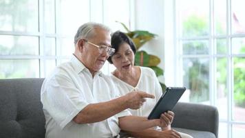 un anciano feliz asiático está haciendo videollamadas, se relaja en casa, sonríe abuelos jubilados mayores sanos, concepto de tecnología de abuelos mayores.