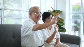 An Asian happy seniors elderly are video calling , relax at home, smiling healthy senior retired grandparents, older grandparent technology concept.