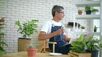 un anciano se relaja con café y lee el periódico en su casa. video