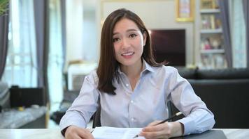 vue d'écran de la tête d'une jeune femme d'affaires asiatique est en ligne en utilisant la vidéoconférence avec des partenaires ou des collègues d'affaires de chez elle. video