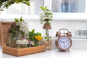 Alarm clock with flowering branches in a wooden box on the windowsill. Spring forward photo