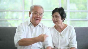 un anciano feliz asiático está haciendo videollamadas, se relaja en casa, sonríe abuelos jubilados mayores sanos, concepto de tecnología de abuelos mayores. video
