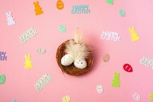 Top view of quail eggs in a nest with feathers on a pink background. Family holiday concept. Greeting card template. copy space. banner photo