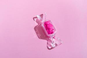 caja transparente en forma de caramelo con piruletas de corazón dulce con sombra dura sobre fondo rosa con espacio para copiar. el concepto de día de san valentín, día de la madre. foto
