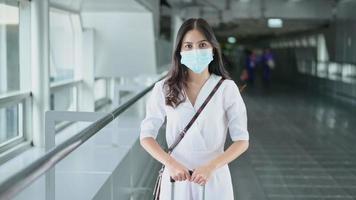 A traveller woman is wearing protective mask in International airport, travel under Covid-19 pandemic, safety travels, social distancing protocol, New normal travel concept . video