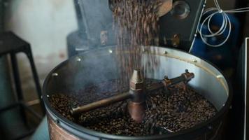 el grano de café se está asando en la máquina tostadora, fumando del café. video