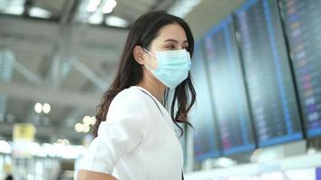 uma mulher viajante está usando máscara protetora no aeroporto internacional, viaja sob pandemia covid-19, viagens de segurança, protocolo de distanciamento social, novo conceito de viagem normal video