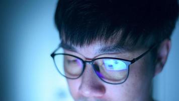 Close up of asian young man wearing the glasses looking on the computer video