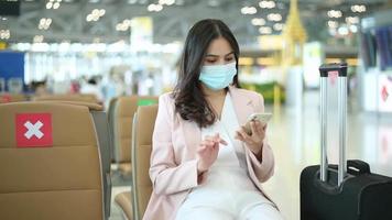 una donna viaggiatrice indossa una maschera protettiva nell'aeroporto internazionale, viaggia sotto la pandemia covid-19, viaggi di sicurezza, protocollo di allontanamento sociale, nuovo concetto di viaggio normale. video