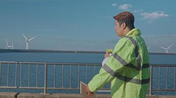 un ingeniero hombre lleva un casco protector en la cabeza, utilizando datos de ingeniería de análisis de tabletas. video