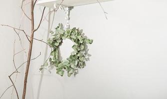 eucaliptus branch wreath hanging on a wall, spring decor in a rustic style home. seasonal decoration for spring holidays. copy space. photo