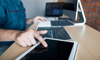 Software developer is pointing to the paper working and analyzing together the code written into the program on the computer. photo
