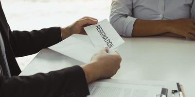 Woman employee takes the handle to the resignation envelope while being handed over to the female manager. photo