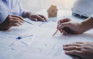 Two architect working at construction site and compass drawing pointing on blueprint with partnership. photo