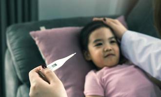 Asian female pediatrician is using a thermometer to measure fever for children photo