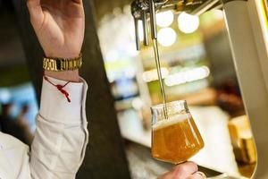 Crop barman pouring beer in glass in a bar photo