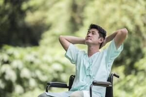 Alone young disabled man in wheelchair at the garden photo