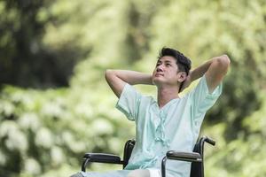Alone young disabled man in wheelchair at the garden photo