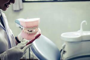 el dentista explica cómo cepillarse los dientes correctamente. foto