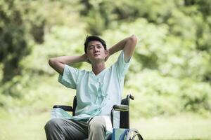 Alone young disabled man in wheelchair at the garden photo