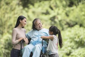 abuela feliz en silla de ruedas con su hija y nieto en un parque, vida feliz tiempo feliz. foto