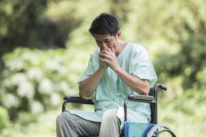 Alone young disabled man in wheelchair at the garden photo