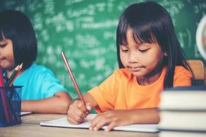 Two girl with crayon drawing at lesson in the classroom photo
