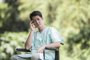 Alone young disabled man in wheelchair at the garden photo