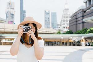 Happy beautiful traveler asian woman carry backpack. Young joyful asian women using camera to making photo during city tour, cheerful emotions, great mood. Women lifestyle outdoor in city concept.