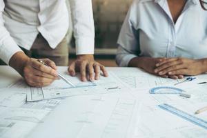 Two architect working at construction site and compass drawing pointing on blueprint with partnership. photo