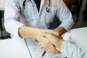 Doctor shaking hands with older patient in the clinic room. photo